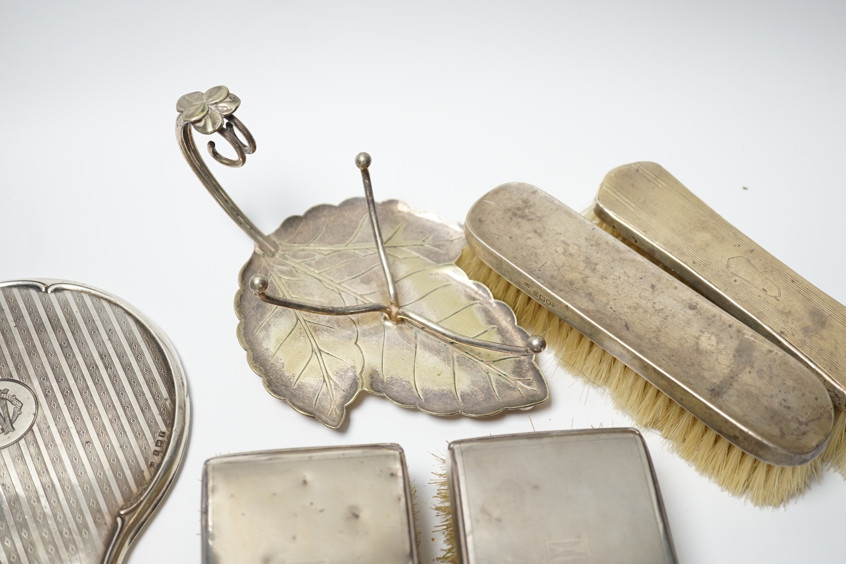 A George V silver mounted hand mirror, Birmingham, 1916, five assorted silver mounted brushes including a pair of clothes brushes and a plated stand.